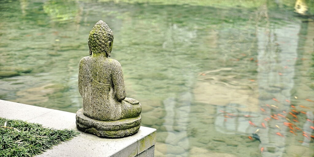 Meditierende Buddha Statue am Teich.