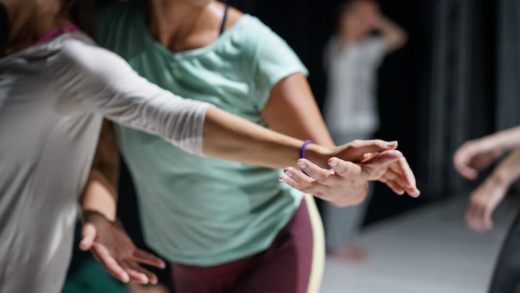 Contemporary Dance Performace, Contact Improvisation, Detailaufnahme Arme und Hände tanzendes Paar, im Hintergrund andere Tänzer