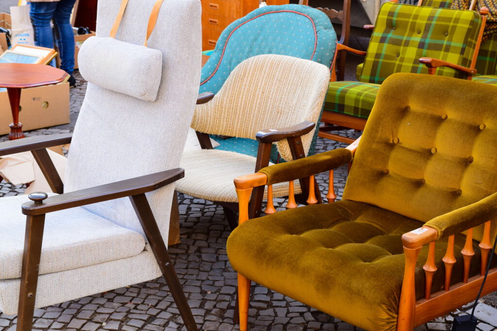 mehrere von Stil und Farbe unterschiedliche Sessel auf Flohmarkt auf Kopfsteinpflaster, alle nach links ausgerichtet mehrere von Stil und Farbe unterschiedliche Sessel auf Flohmarkt auf Kopfsteinpflaster, alle nach links ausgerichtet