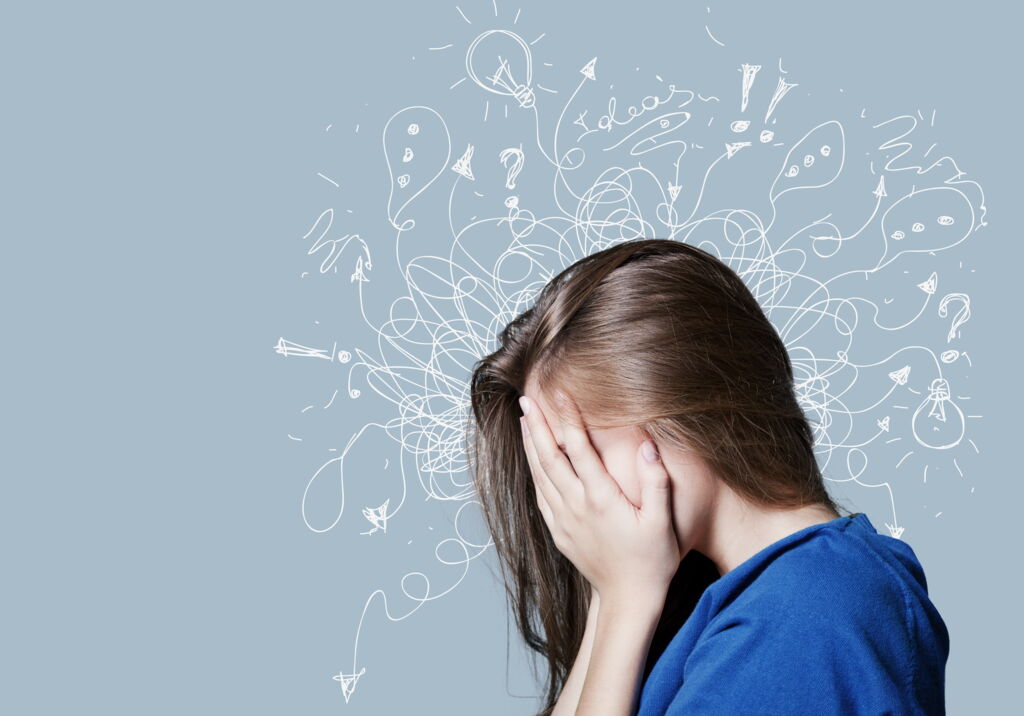 junge Frau vergräbt das Gesicht in ihren Händen. Weiße Strichzeichnungen auf grauem Grund symbolisieren Verwirrung und Überflutung in ihrem Kopf