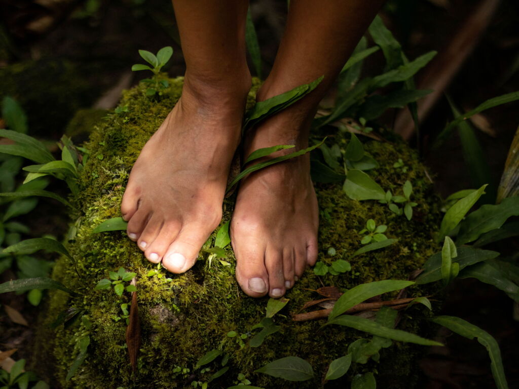 nackte Füsse auf moosigem Waldboden mit Sonnen-Lichtfleck